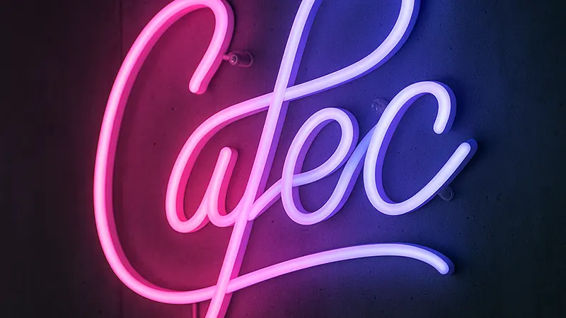 تابلو نئون سفارشی با نور نارنجی نصب‌شده روی دیوار آجری تیره در فضای داخلی فروشگاه مدرن